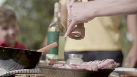 close-up of woman using pepper mill over piece of meat