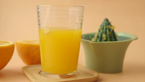 glass of freshly squeezed orange juice with oranges and a citrus juicer