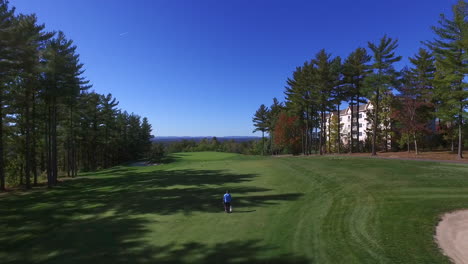 Aerial-shot-of-a-man-walking-on-a-golf-course-on-a-beautiful-day