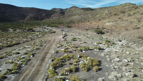 waste scattered along the roadside in the desert landscape of mulege, baja california sur, mexico - aerial pullback shot