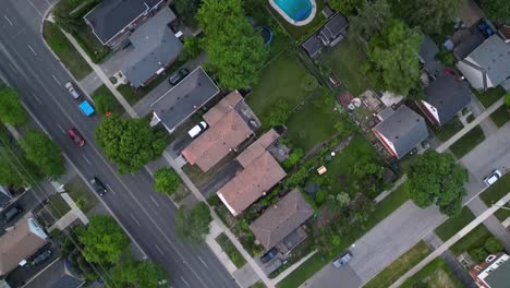 top down aerial of cars driving along streets in suburban middle class neighbourhood with houses