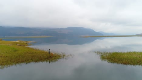 Man-standing-with-his-dog-near-lakeside-4k