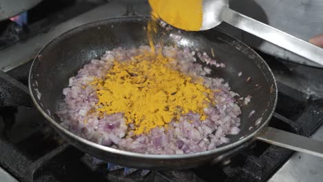 adding turmeric to sautéed onions in pan