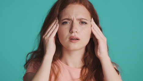 Redheaded-girl-in-front-of-camera-on-turquoise-background.