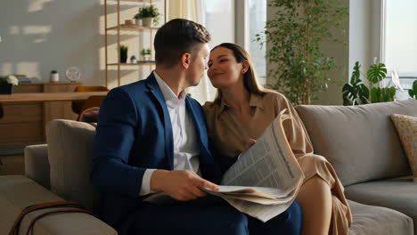 couple shares an affectionate moment while reading newspaper at home