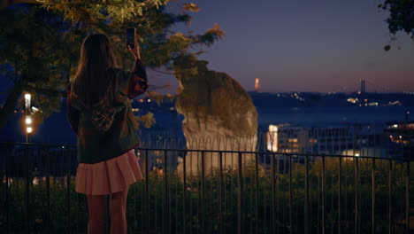 woman tourist making photo evening city on smartphone standing observation deck