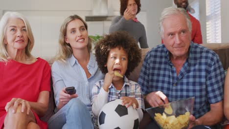 Video-Einer-Gemischten-Familie,-Die-Auf-Der-Couch-Sitzt-Und-Ein-Fußballspiel-Verfolgt