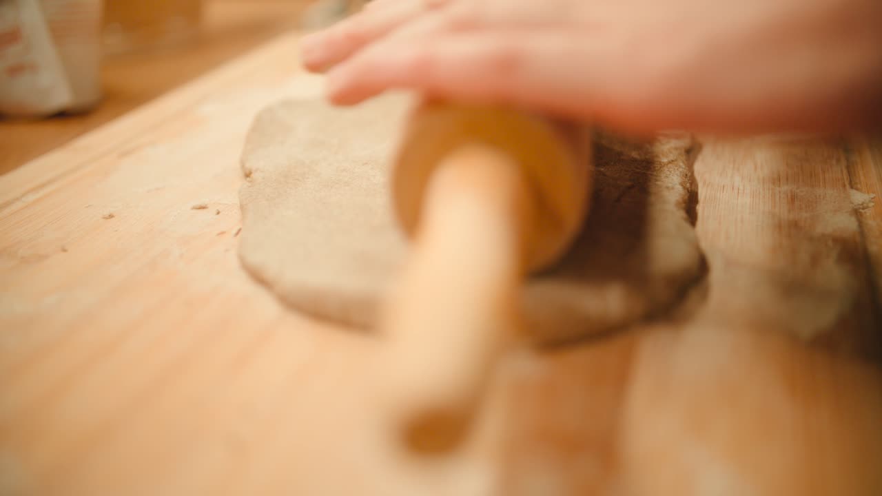 作りたてのクッキー生地の上で、両手で麺棒をゆっくりと転がすスローモーション映像