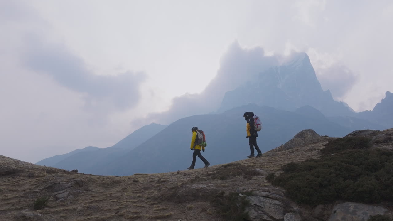 Two travelers bond during Everest Base Camp trek at Dingboche, Nepal. Misty weather creates a romantic and soulful Himalayan atmosphere for travel and tourism experience