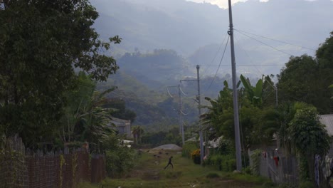 rural path leading to a mountain valley with distant houses and a walker