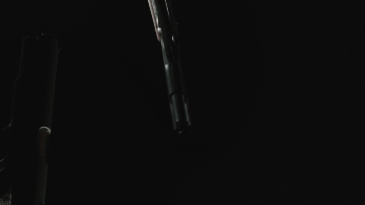 Pistols on the dark background are falling in slowmotion