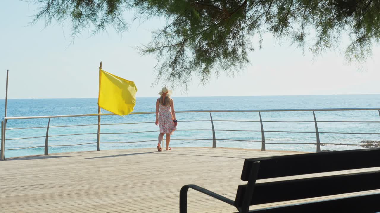 mujer con vestido de verano caminando hacia el océano atlántico en tenerife, vista trasera