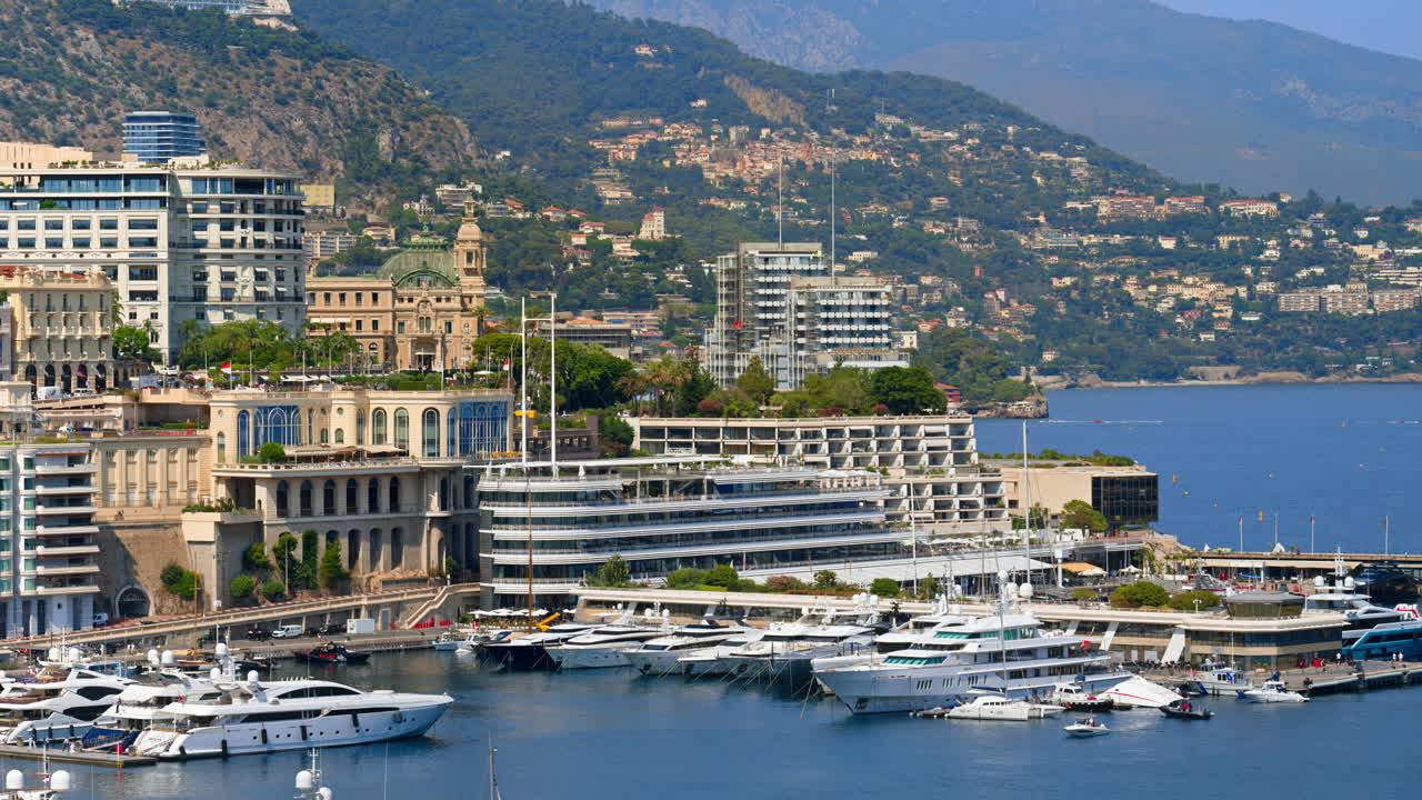 Aerial view of white boats docked in the Monaco Marina with the skyline on the background