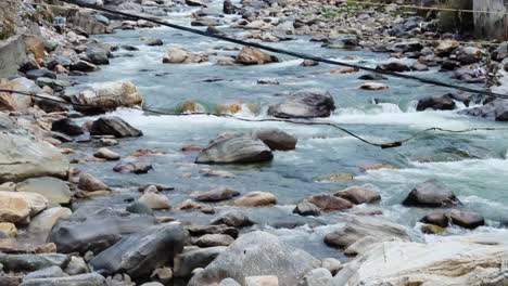 Dampf-Steigt-Aus-Natürlichem,-Heiligem-Thermalwasser-Auf,-Während-Kaltes-Wasser-Aus-Den-Bergen-Fließt