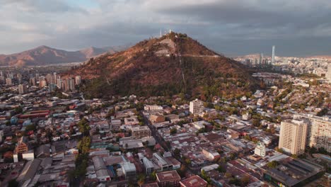 Sonnenuntergang-Luftaufnahme-In-Richtung-Glühendes-Weitläufiges-Stadtbild-Rund-Um-Den-Berg-Cerro-San-Cristobal