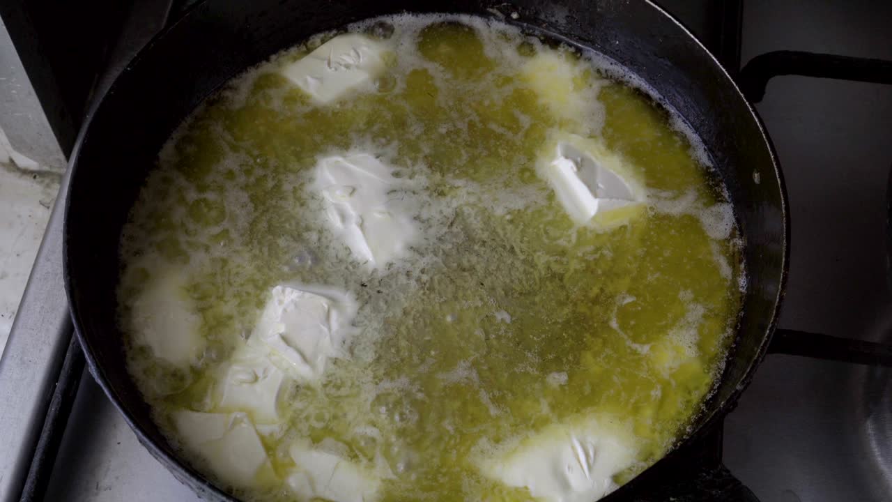 trozos de mantequilla blanca se derriten en una sartén caliente. el derretimiento en la sartén de metal hierve, silba y gorgotea. cocinar. de cerca. vista superior. 4k.