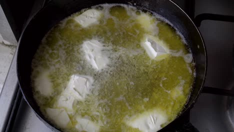 pieces of white butter melt in a hot pan. the melt in the metal pan boils, hisses and gurgles. cooking. close up. top view. 4k.