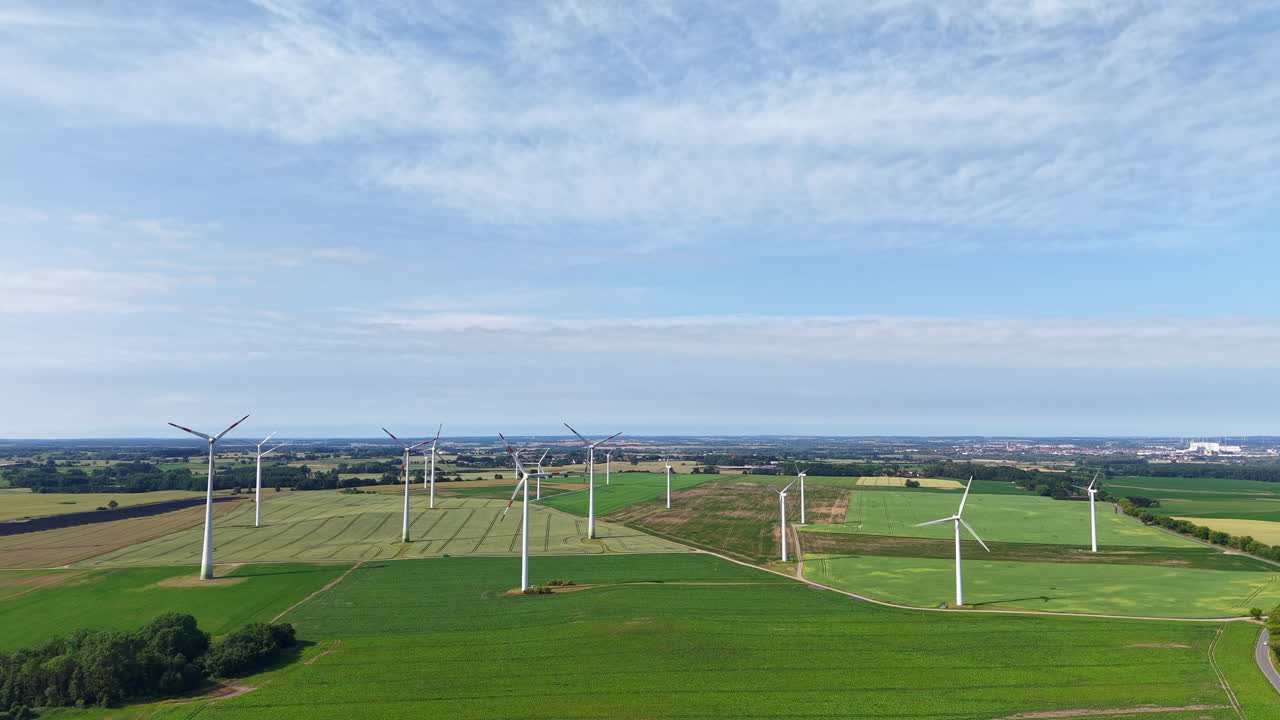 There are many wind turbines in the fields and they turn