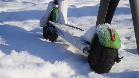 electric scooter abandoned in the park during snowy winter closeup