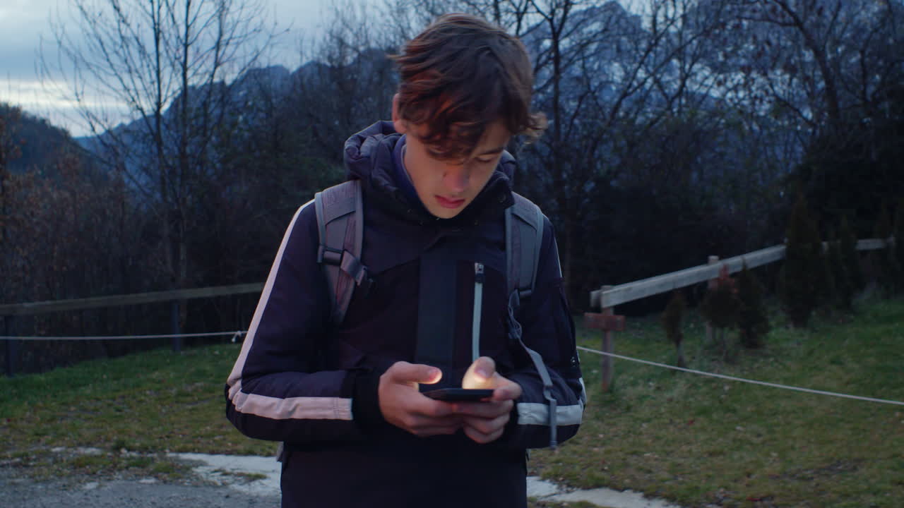 Teenager using a smartphone in a mountainous landscape