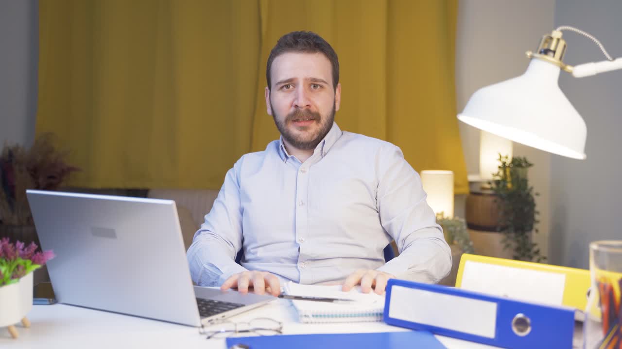 Uomo lavoratore da casa che guarda la telecamera con paura e dubbio.