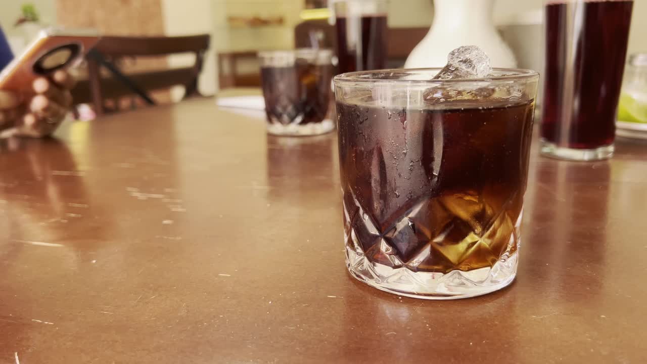 sweeping a cafeteria table with different cola drinks and person consulting the cell phone in the background