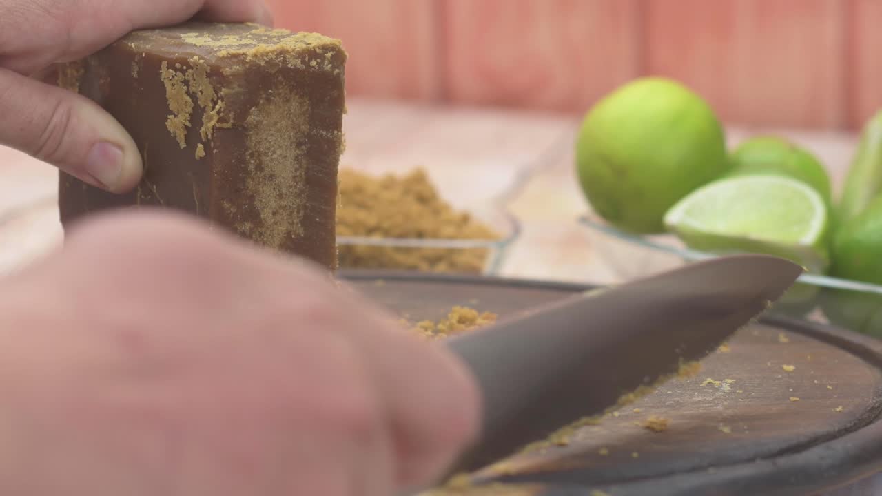 Slicing brown sugar block, fresh limes beside, kitchen preparation