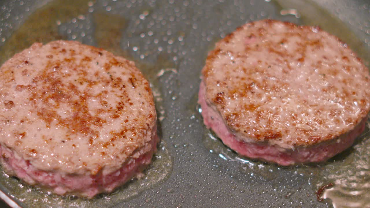 Top View of Aberdeen Angus Beef Burgers Cooking with Oil Spitting Up in Slow Motion. High Fat Patties Being Cooked. Tasty Food Clip