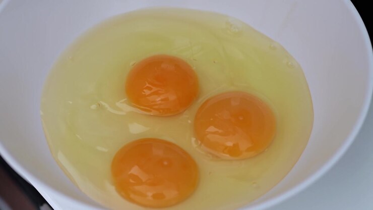 Raw Egg with Two Orange Yolks and Egg White in Bowl for Kitchen Preparation
