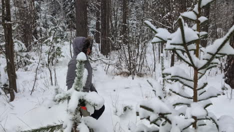 a person hiking in a snowy forest with a saw in hand