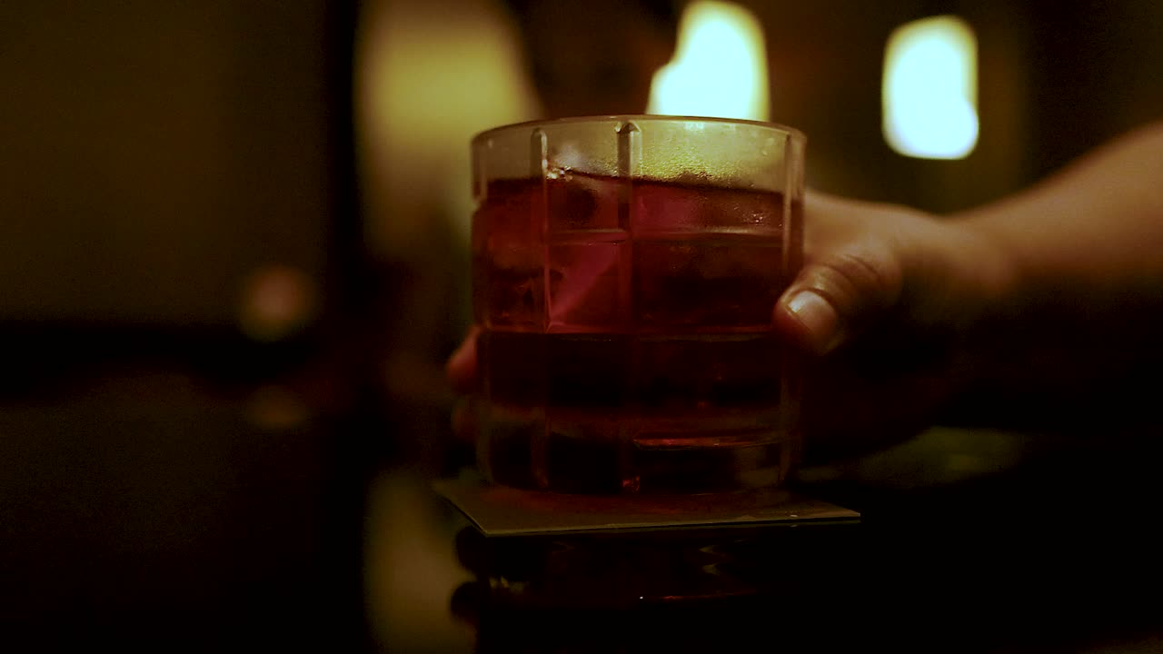 una mano alcanza un vaso de cóctel