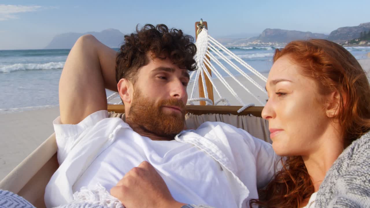 pareja interactuando entre sí en una hamaca en la playa 4k