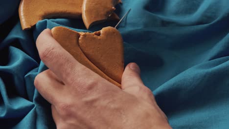 men's hands break sugar cookies candy in the shape of a heart.