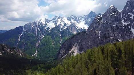 forward drone shot of vrsic pass, slovenia, on a sunny day with some clouds