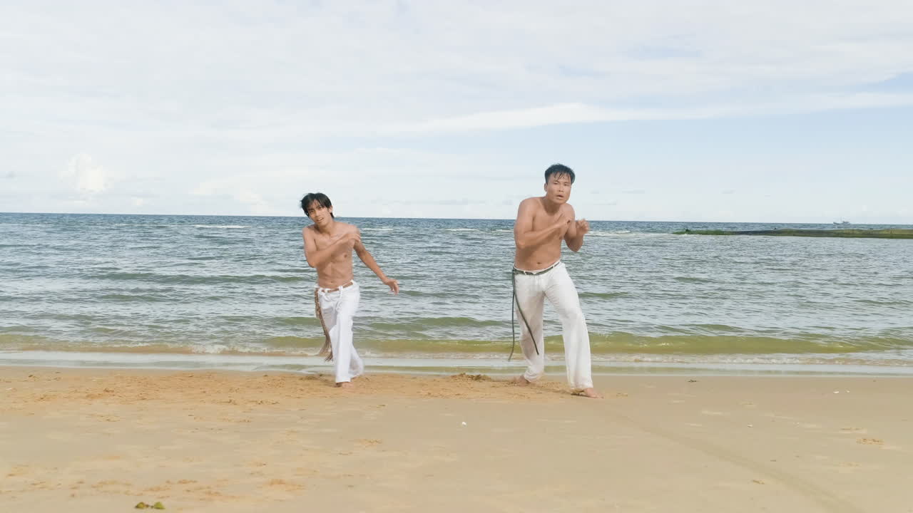 두 남자가 해변에서 카포에라를 춤추고 있다