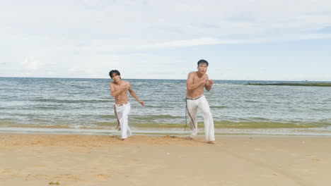 two men dancing capoeira on the beach