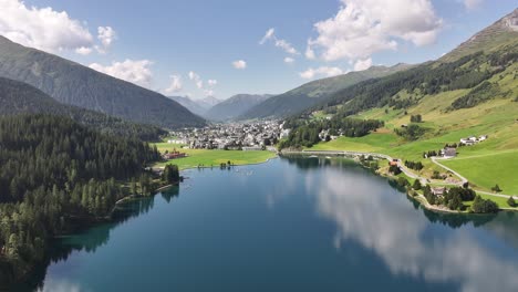 Drone view of Davos, a town in the Graubünden canton of Switzerland, with a calm, reflective lake surrounded by serene nature