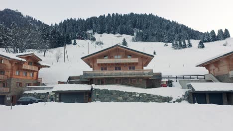 low angle aerial of beautiful wooden chalet in snow covered rural landscape