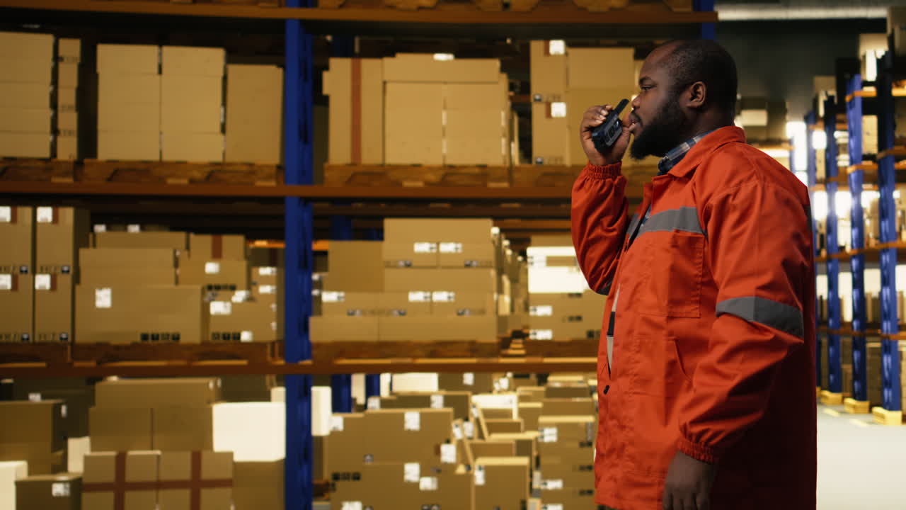 Radio walkie-talkie portatile, in un centro di distribuzione, membro del personale di colore.