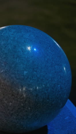 vista de cerca de las esferas de granito iluminadas por la noche, mostrando sus superficies lisas y pulidas y la iluminación suave y azul