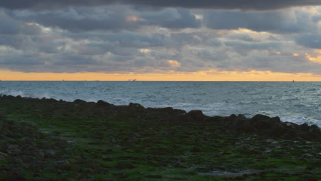 northsea waves hitting a dyke at sunset