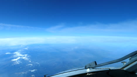 cockpit view of clouds passing above snow capped alps mountain ranges