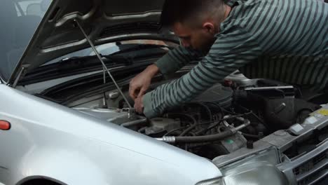 young mechanic works on fixing an old car engine