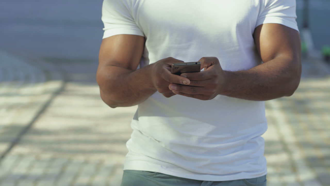 Cropped shot of African American using smartphone outdoor.