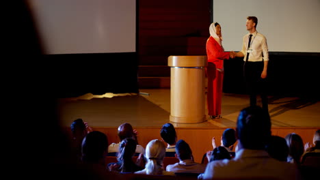 gente de negocios multiétnica estrechando la mano en el escenario en el seminario de negocios en el auditorio 4k