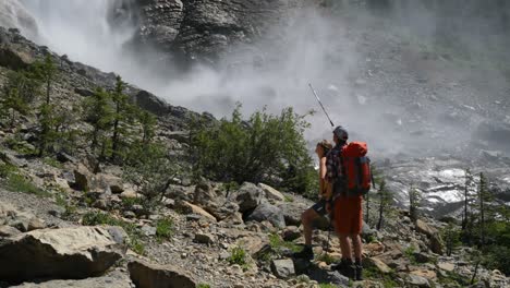 front view of young caucasian hiker couple with backpack standing in forest and pointing away 4k