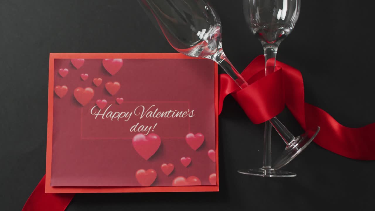 Happy valentine's day text over champagne glasses and red ribbon