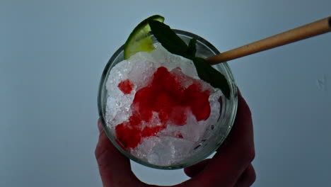 hand taking cocktail glass closeup. overhead shot bartender holding iced mojito