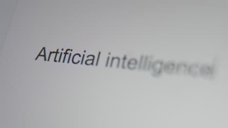 a close up of a digital screen showing a text cursor and the words "artificial intelligence" being typed