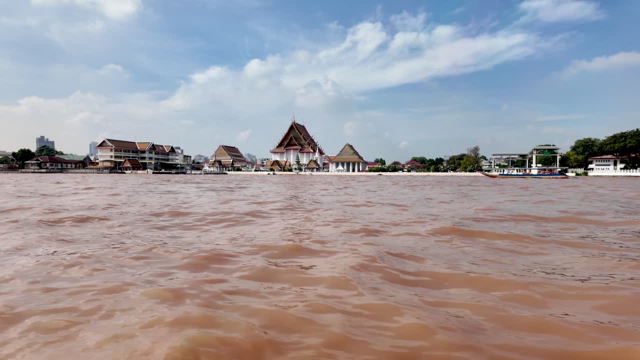 Scenic view of the Chao Phraya River in Bangkok, featuring traditional Thai temple architecture along the water